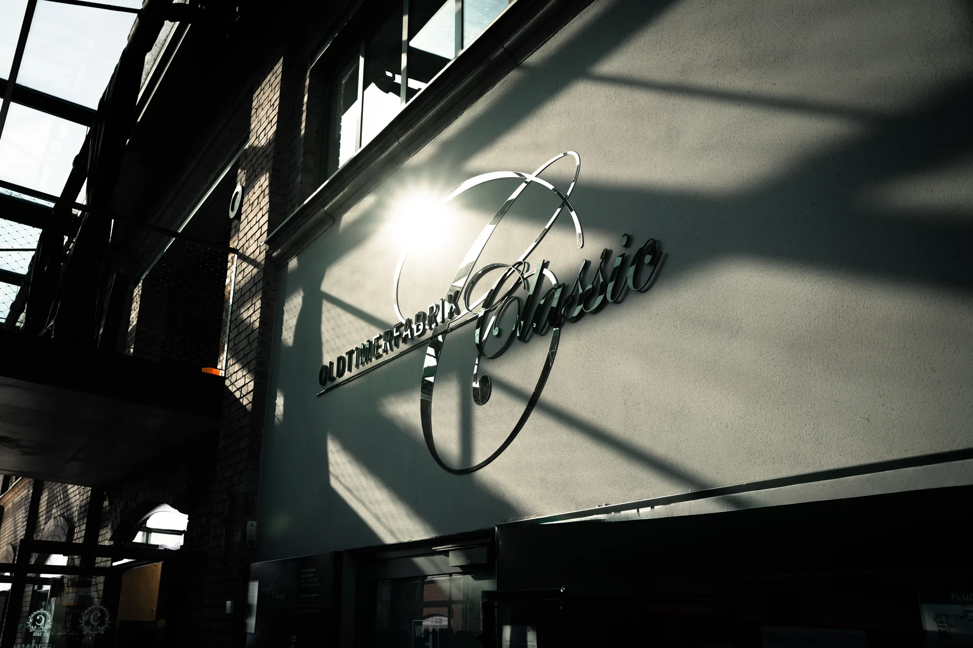 Verchromter Schriftzug Oldtimerfabrik Classic an der Hallenwand im Gegenlicht